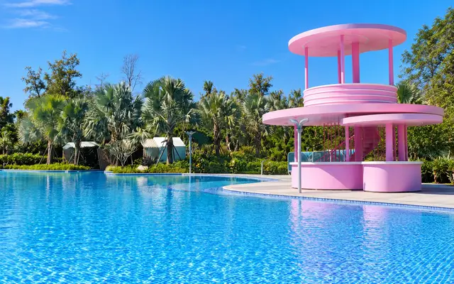 Outdoor pool with palm trees and a pink tower