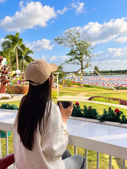 Guest with a coffee on a balcony above the lawn and lake